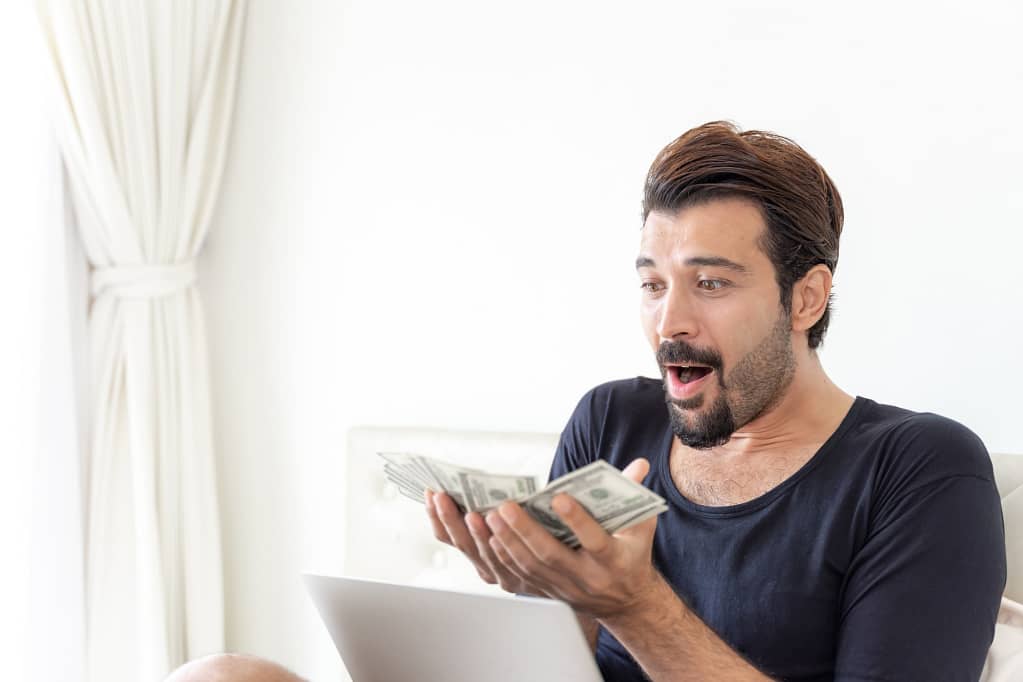 Man excitedly holding cash earned from recycling an old family car