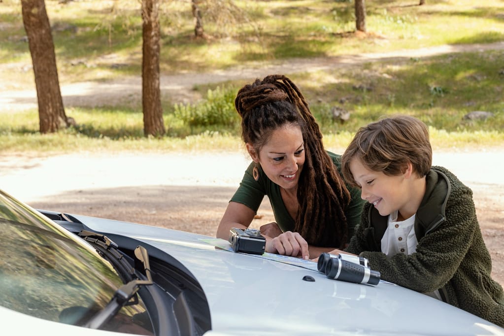 Mother and child learning about car recycling outdoors, discussing sustainability and exploring the value of reusing materials.