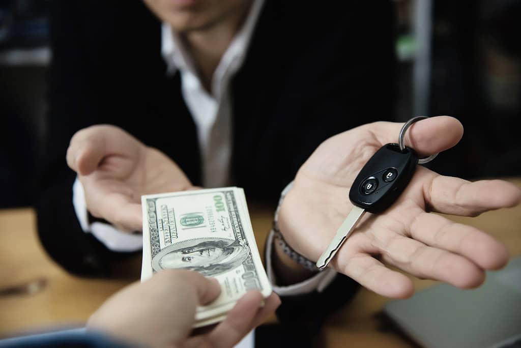 Exchanging scrap car keys for cash, showcasing the financial benefits of recycling cars.