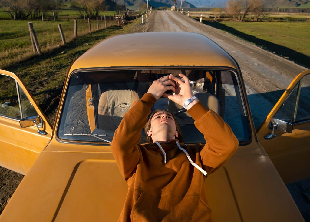 Man Relaxing on Old Car, Highlighting Stress-Free Benefits of Scrapping