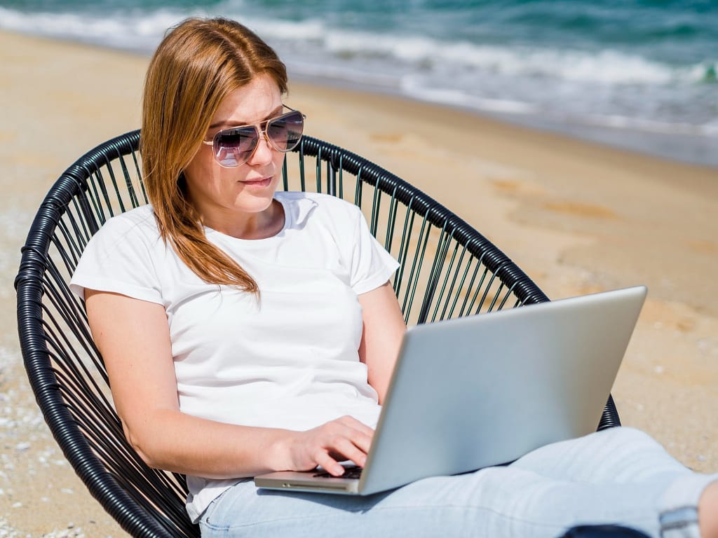 Woman researching top websites for quick car recycling offers on a laptop by the beach